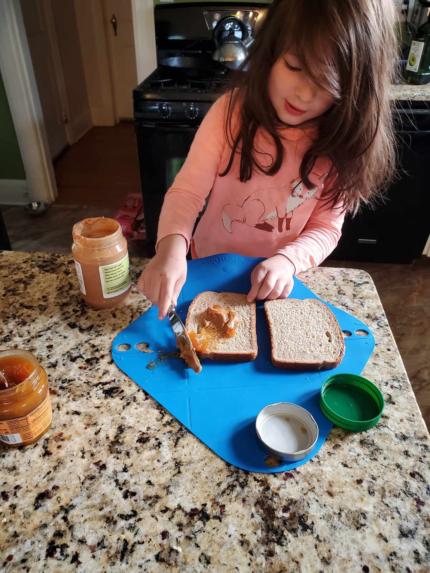 Young girl making peanut and butter sandwich using Qrumbles